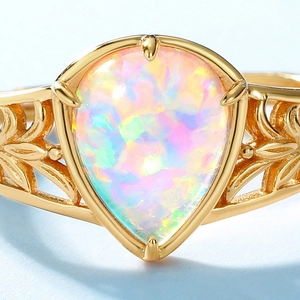 Vintage gold pear-cut opal ring with leaf engravings on a minimalist blue base