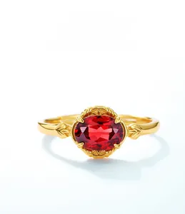 Macro shot of oval red garnet stone with vintage gold floral relief and leaf patterns