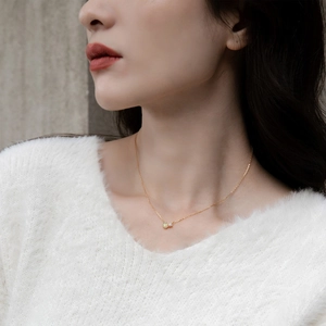 Makro-Detail der goldenen Opal-Halskette mit Zirkon auf weißem strukturiertem Pullover