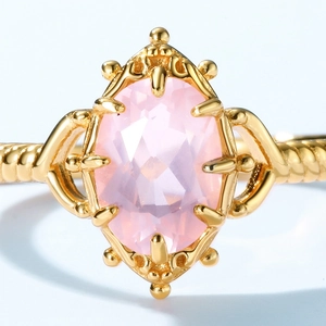 Macro shot of vintage crown ring with pink oval crystal and intricate gold lace detail