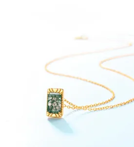 Détail macro du pendentif en agate mousse verte avec cadre doré gravé de rayons