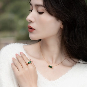 Close-up of gold silver ring and necklace set featuring rectangular green malachite stones