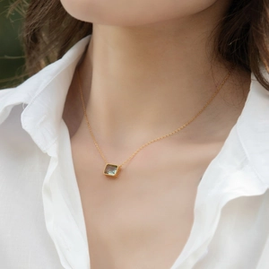 Macro detail of square emerald-cut green crystal pendant on gold vermeil chain necklace