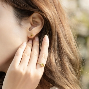 Macro detail of 925 silver gold-plated peridot stud earrings and ring set on model