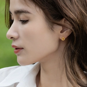 Close-up of teardrop yellow crystal earring with beaded gold border on female model