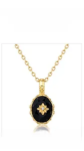 Close-up of gold oval black onyx pendant with an intricate gold starburst pattern