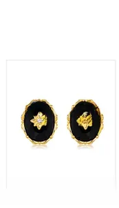 Detail view of retro oval black agate earrings with golden starburst and ornate frame