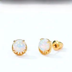 Vue détaillée des boucles d'oreilles opale blanche avec sertissage griffe en or et base ciselée