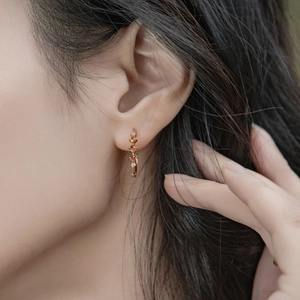 Boucles d'oreilles créoles en argent S925 or rose avec grenats orange sur un modèle