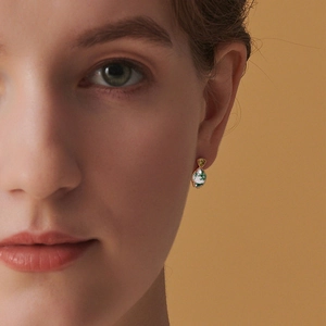 Boucles d'oreilles pendantes dorées avec agate mousse sur un modèle sous lumière chaude