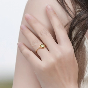 Close-up of a minimalist gold S925 silver ring with a green peridot gemstone on a model