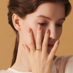 Primer plano de un anillo minimalista de plata S925 con tres gemas rojas en el dedo de una modelo