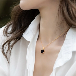 Detail van een minimalistische gouden ketting met blauwe zandsteen hanger op een model
