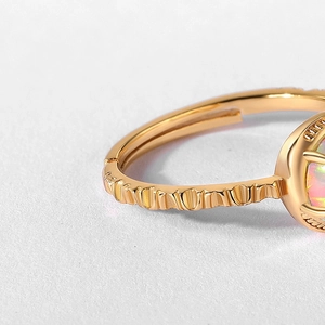 Macro view of adjustable gold-finish opal ring with intricate embossed texture