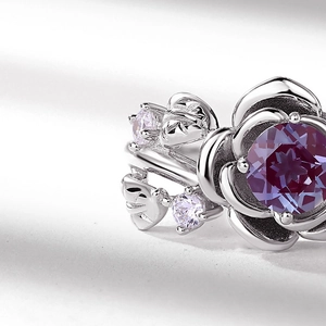 Macro shot of silver rose ring featuring a large red alexandrite stone and leaf details