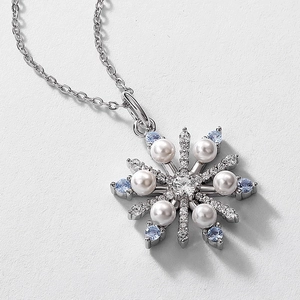 Detail view of a 925 silver snowflake pendant with pearls and blue gemstones