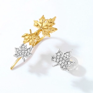 Asymmetric maple leaf earrings in gold and silver finish with sparkling micro-pave crystals