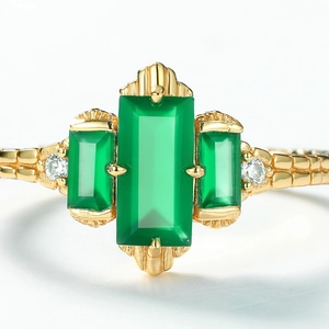 Macro detail of retro gold ring featuring three green stones and textured metal band