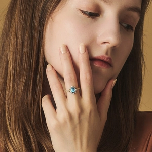 Detail view of a sky blue topaz ring with rectangular cut and gold relief texture on the band