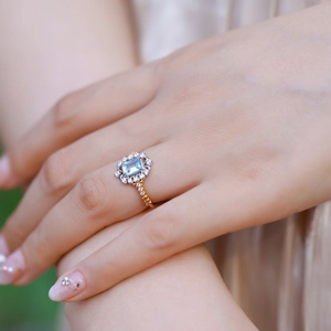 Elegant gold S925 silver ring featuring blue topaz stone with halo diamonds on hand