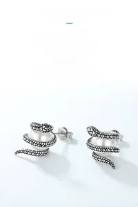 Vue détaillée de boucles d'oreilles serpent en argent avec perle et yeux en pierre verte