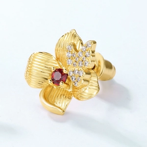 Macro shot of 925 silver 10K gold flower stud earrings with red garnet and crystal