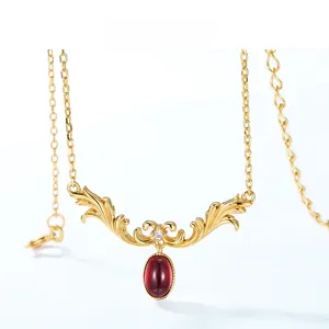 Detail of vintage gold necklace with red oval stone and ornate scrollwork pattern