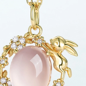 Detailed macro shot of a golden bunny pendant with pink quartz stone and zircon flowers