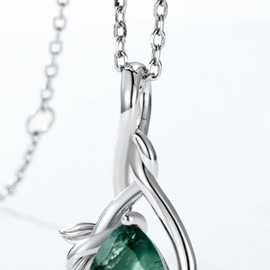 Macro shot of silver pear-cut green gemstone pendant with leaf-style setting details