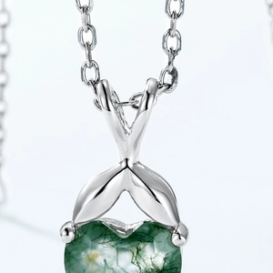 Vue macro d'un pendentif coeur en agate mousse verte avec bélière et chaîne en argent