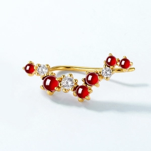 Elegant gold curved earrings with natural garnets and white zircons on a white background