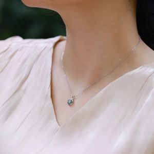 Gros plan d'un collier pendentif cœur en agate mousse verte porté par un mannequin