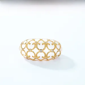Detail of vintage gold filigree patterns with small zircons on a white enamel ring