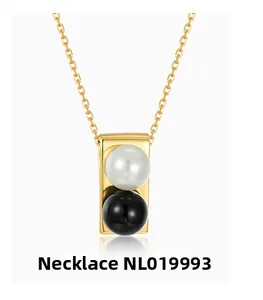 Detailed macro view of dual-tone white and black pearl pendant on golden chain necklace