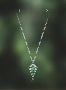 Macro detail of kite-shaped moss agate necklace with green inclusions in silver setting
