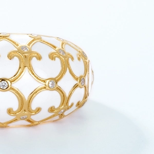 Macro shot of gold floral filigree over white enamel with sparkling crystal details