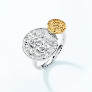 Detailed macro view of two-tone S925 silver coin ring with vintage embossed crest patterns