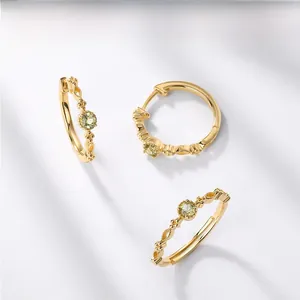 Detailed close-up of vintage gold earrings with round green peridot stones on white background