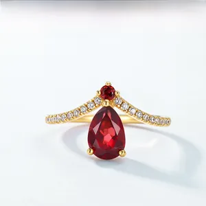 Macro view of a V-shaped 18K gold ring featuring pear-cut and round red rubies