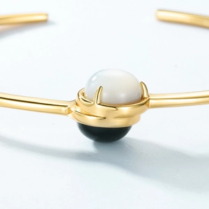 Macro detail of open bangle featuring white shell pearl and black onyx stone inlay