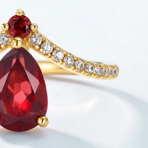 Macro shot of V-shaped S925 silver gold plated ring with pear-cut garnet and zircon