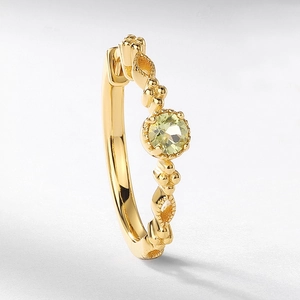 Macro detail of gold vintage earring featuring peridot gemstone and ornate metalwork