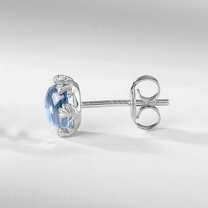 Gros plan d'une boucle d'oreille en argent S925 avec topaze bleue et griffes bois