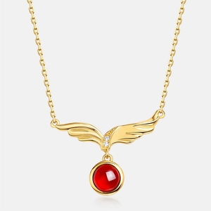 Dettaglio della collana con ciondolo a ali dorate con granato rosso e accenti di zircone