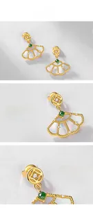 Macro detail of gold-plated fan earrings with white shell and green jade inlay
