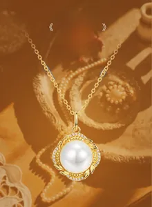 Detail of shell pearl pendant with golden leaves and white zirconia on a gold chain