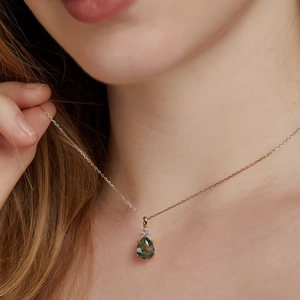 Detailopname van de mosagaat hanger in druppelvorm met zirkonia op een gouden ketting