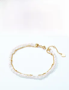 Close-up of double-layer pearl bracelet with gold chain and heart charm detail