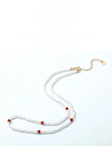 Détail de perles baroques et agate rouge avec pendentif coeur doré sur la chaîne