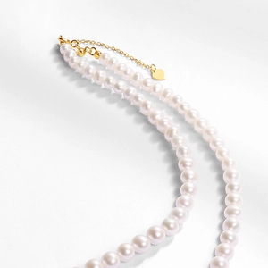 Détail de perles naturelles avec pendentif cœur doré et chaîne en métal ajustable